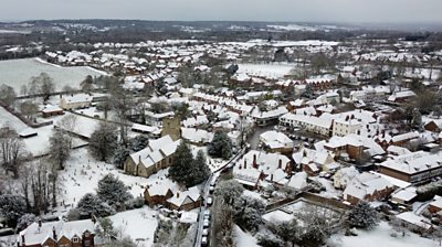 Drone footage shows the county covered in snow as a layer of white settles on homes and trees.