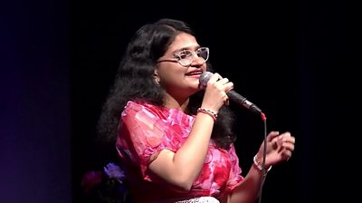 suchetha satish singing with a microphone in her hand