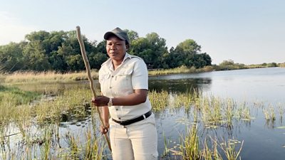 Cindy Mothogaathobogwe holding a long pole on a canoe