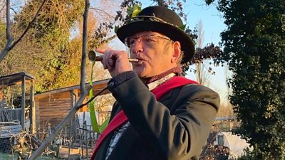 Ian White blow a horn as part of wassailing