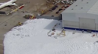 Fire suppression foam covers parking lot at a Houston hangar