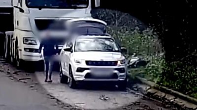 Man fly-tipping a black refuse sack in a lay-by.