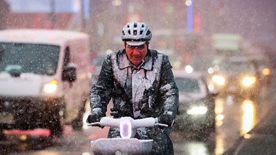 A man rides a bicycle through wind and snow during a Nor'easter winter storm in Times Square in New York