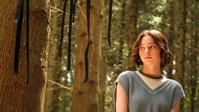 Pip (Emma Myers) is pictured in a forest, where black ribbons hang from a tree