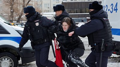 A woman being dragged away by three police officers in Moscow