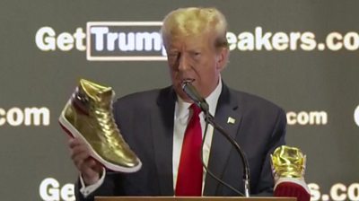 Donald Trump holding golden sneaker while talking