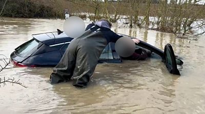 A stranded driver is helped from his car.