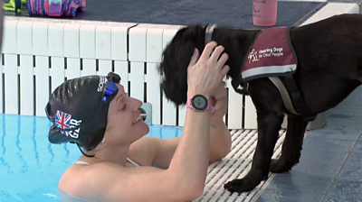 Suzanna Hext in the pool stroking her dog who is standing on the edge