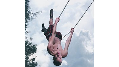 Olly Alexander is pictured upside down on a swing