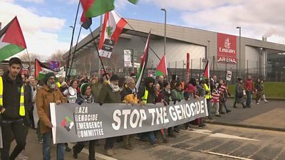 Gaza protestors holding a 'stop the genocide' banner and Palestinian flags march on the Emirates Arena in Glasgow.