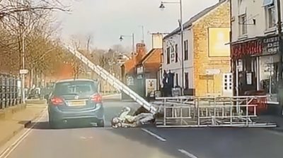 Scaffolding falling into the road and hitting a passing car.