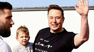 Elon Musk carrying son X AE A-XII and waving to cameras