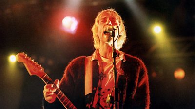 Kurt Cobain performing live with his eyes closed and playing his guitar