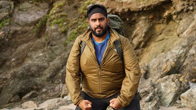 Eshaan Akbar flexes his muscles in walking gear during filming for Pilgrimage: The Road Through North Wales.
