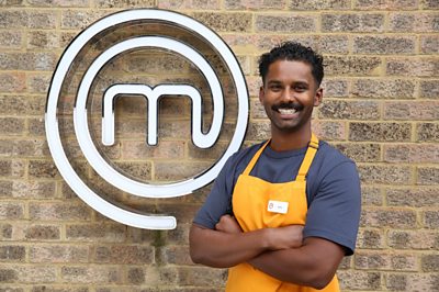 Man wearing chefs apron smiling in front of MasterChef M