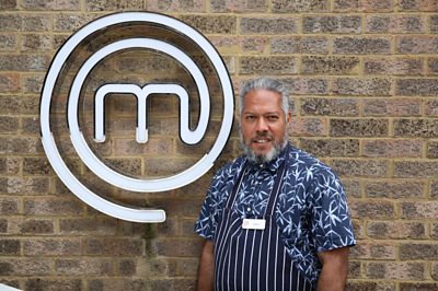 Man wearing chefs apron smiling in front of MasterChef M