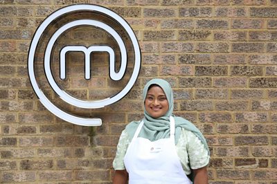 Woman wearing chefs apron smiling in front of MasterChef M