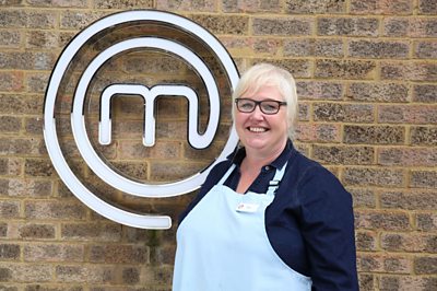 Woman wearing chefs apron smiling in front of MasterChef M
