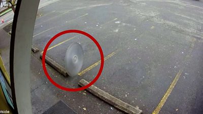 Saw blade flying through car park with red ring around it
