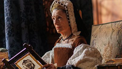 Harriet Walter as Lady Margaret Pole looks up at someone offscreen whilst embroidering a piece of fabric 