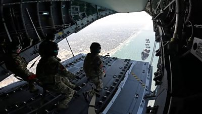 Military personal in aircraft airdropping aid