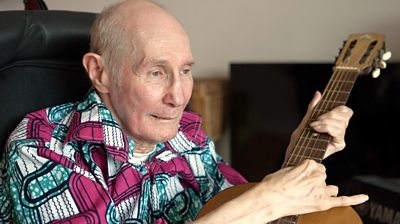Care home resident John playing a guitar