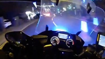 view from the police body worn camera of an officer on a motor bike with blue lights flashing
