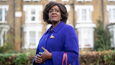 Sharon D Clarke as Carmel Walker, stood in front of a row of terraced houses