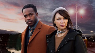 RMP Sergeant Davis Lindo (Romario Simpson) and DS Lara ‘Bart’ Bartlett (Hannah Donaldson) are pictured against the backdrop of a harbour with a bright light in background