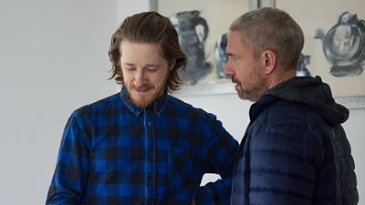 Franny (Adam Nagaitis) smirks as he looks to the floor and stands beside Chris (Martin Freeman).
