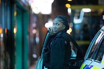 A female police officer steps out of a police car