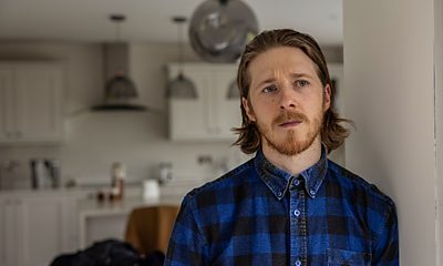 A man with a mullet hair style in a kitchen