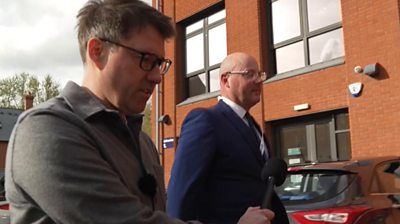 A BBC reporter is following a councillor through a car park