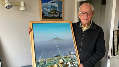 Artist Norman Parker holds one of his paintings of Glastonbury Tor