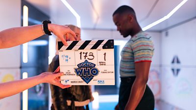 A pair of hands hold a clapperboard as Doctor Who's Ncuti Gatwa and Millie Gibson get ready to film a scene