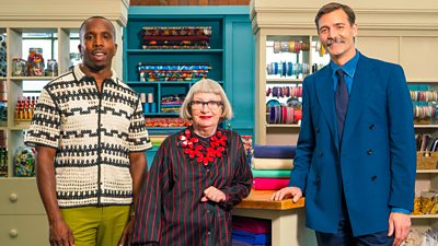 Kiell Smith-Bynoe stands next to judges Esme Young and Patrick Grant in The Great British Sewing Bee studio 