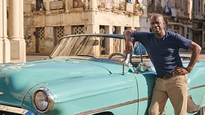 Clive Myrie leaning on a classic blue car