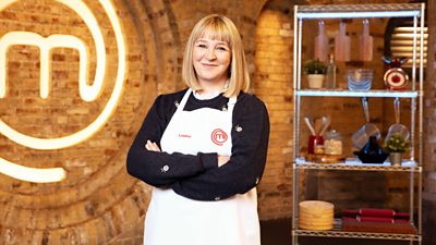 woman in the masterchef kitchen with her arms folded and smiling