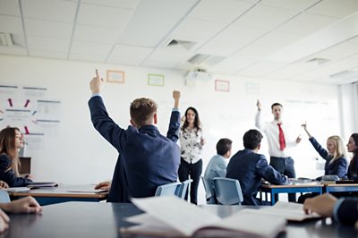 Children with hands up in a school classroom