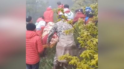 Rescue team carries a body wrapped in cloth on a stretcher