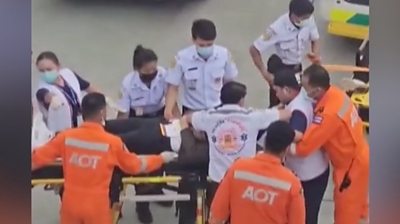 A passenger injured by severe turbulence is carried off flight SQ321 at Bangkok airport.
