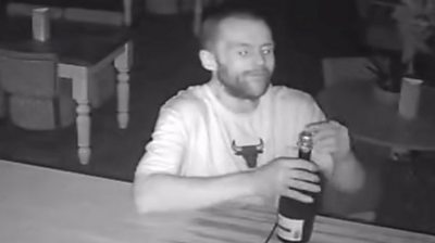 Man opens a bottle of Prosecco at a bar.