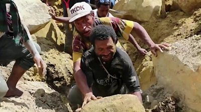 Men struggling to lift a boulder