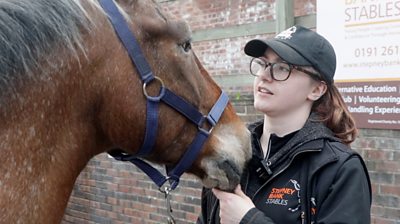 Morgan Place, Youth Project Coordinator at Stepney Bank Stables, stood beside William the horse