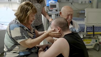 Woman looking at a man and touching his face