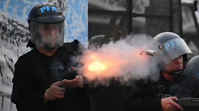 Riot police officer fires his gun