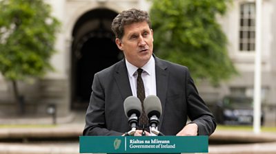 Green Party leader Eamon Ryan at a press conference outside Leinster House. He is standing a lectern with microphones