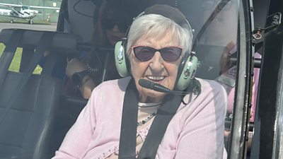 Gwen Jinks wearing a headset in a helicopter