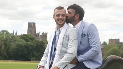 Newlyweds John, 39, and Les, 50, wearing suits and sat atop Durham's riverside bull sculpture.