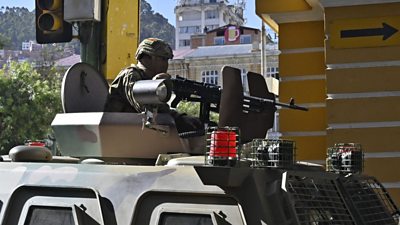 Soldier on top of an armoured vehicle, holding a gun